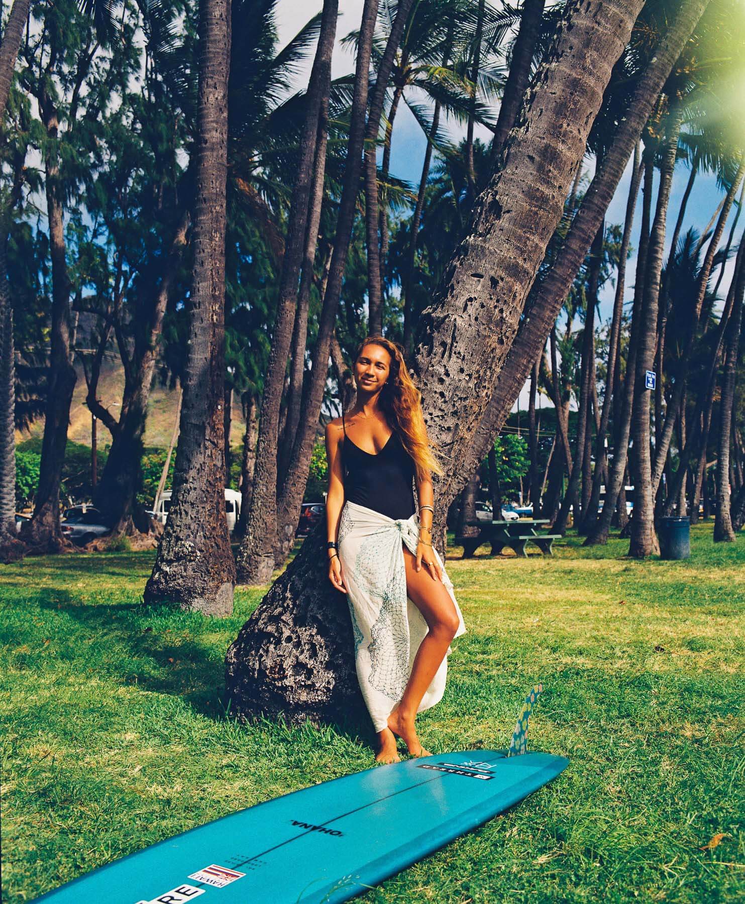 woman in flowy skirt posing against palm tree