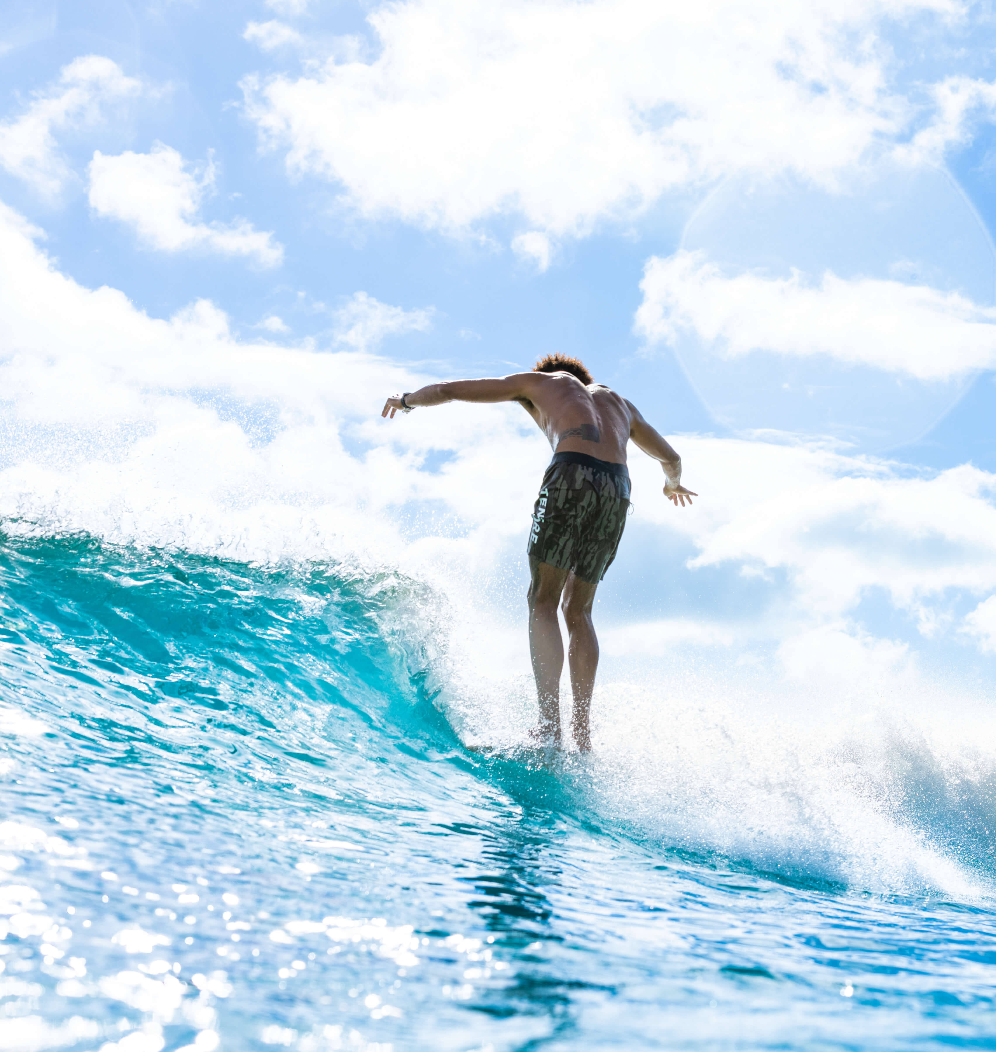 man balancing on surfboard in camo swim trunks