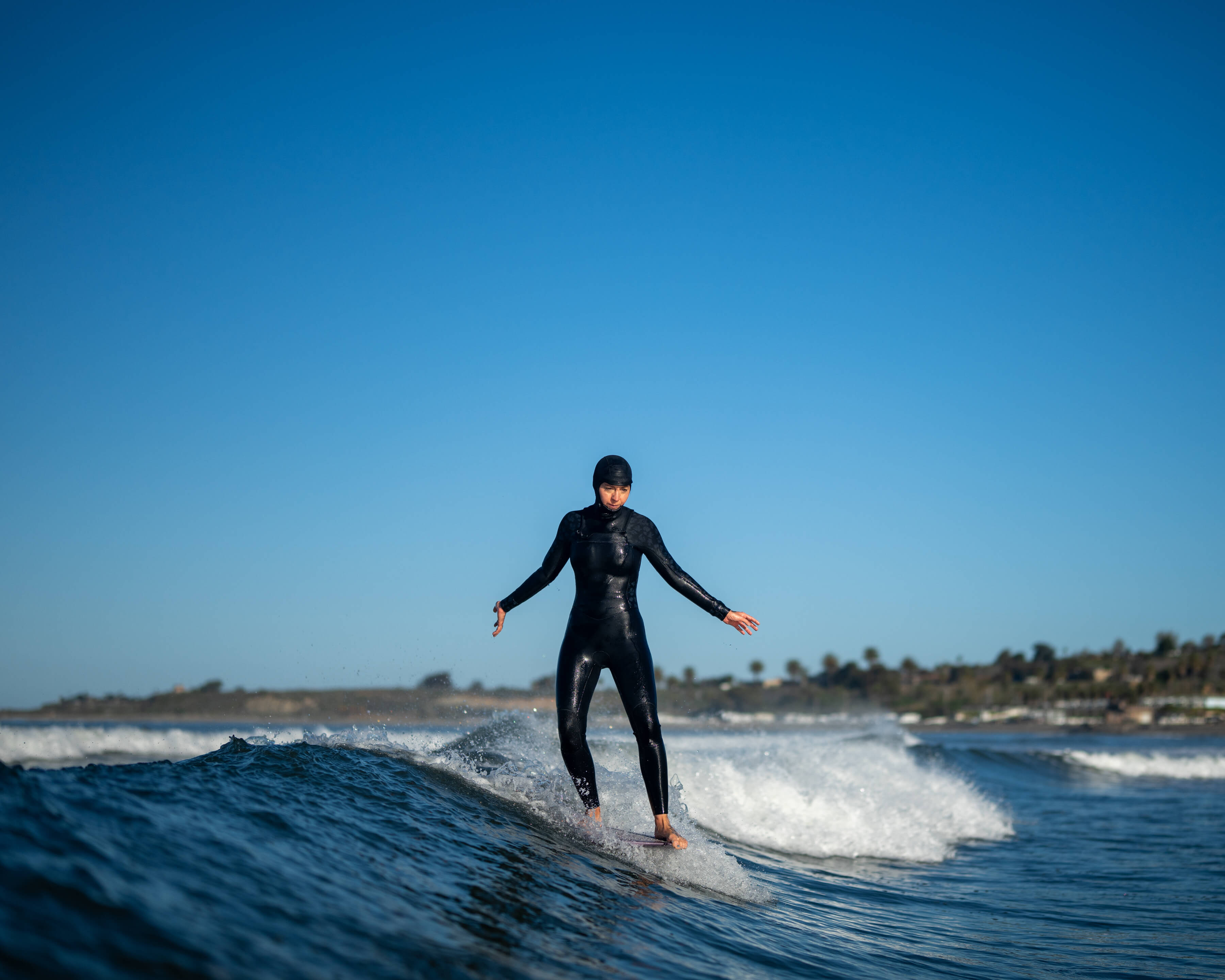 closeup of woman in full wetsuit riding a wave